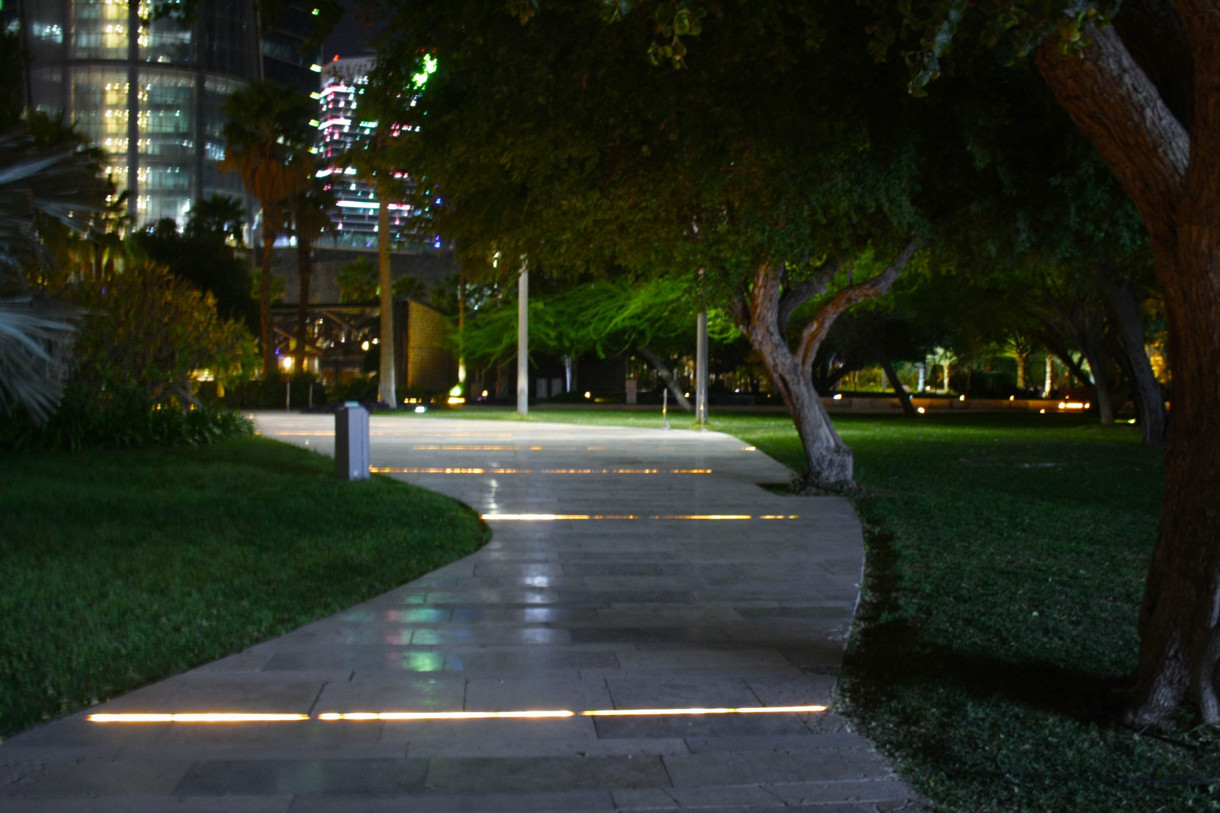 Illuminated garden pathway between trees in Al Shaheed Park